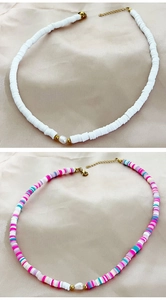 Detail of bohemian handmade clay necklaces with pearls and gold beads on satin fabric