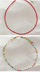 Macro shot of colorful seed bead necklaces with gold clasps on silk fabric background