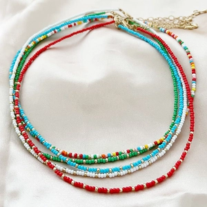 Set of four colorful beaded necklaces in red, white, blue, and rainbow boho style