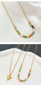 Detail of layered gold heart necklace with colorful beads and white pearls on a tray