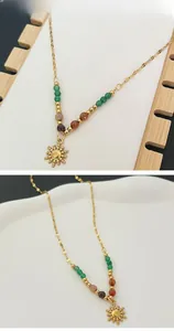 Detail of 18K gold sun pendant necklace with multicolored bohemian beads and chain