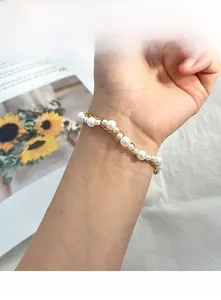 Détail d'un élégant bracelet de perles et chaîne dorée au poignet d'une femme