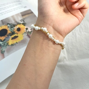 Bracelet élégant à plusieurs rangs de perles et chaînes dorées au poignet
