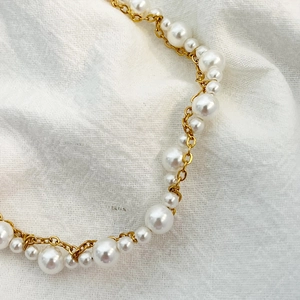 Bracelet élégant en perles et chaîne dorée avec perles blanches sur fond minimaliste