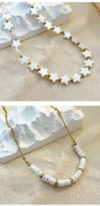 Detail of vintage French star beads and golden stainless steel necklaces on a white stone