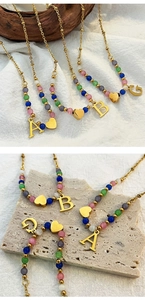 Detail of colorful beads and gold initial pendant necklace with small heart charm