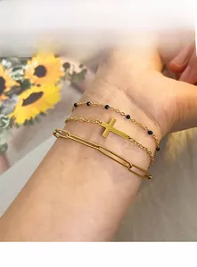 Detailed view of 18K gold plated triple layered bracelet with cross and black beads