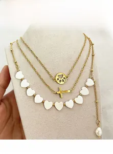 Detailsicht der goldenen Halskette mit Herzperlen, Kreuzanhänger und Barockperle im Lagen-Look