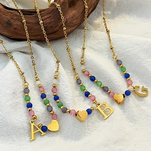 Handmade colorful beaded letter pendant necklace with gold chain on rustic fabric