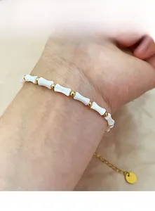 Détail d'une chaîne dorée réglable avec perles de nacre blanche sur bracelet minimaliste