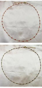 Detail of minimalist gold necklaces with delicate red and black beads on silk background