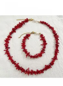 Detailed shot of red coral-style beaded necklace with gold clasp and pearl detail