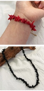 Close-up of vintage irregular red and black natural stone beaded necklaces on wood