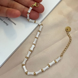 Bracelet en acier titane avec perles en nacre blanche et maillons bambou dorés élégants