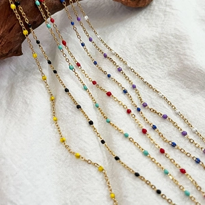 Retro stainless steel gold chain necklace with colorful enamel beads on linen background