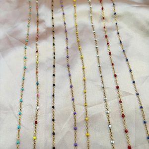 Minimalist gold stainless steel necklaces with colorful enamel beads on silk background