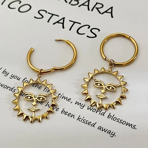 Golden stainless steel hoop earrings with artistic sun face pendants on vintage card