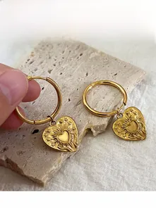 Détail de boucles d'oreilles cœur doré avec reliefs soleil, étoiles et gravure LOVE
