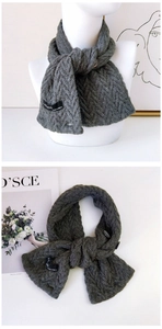 Détail de l'écharpe en tricot gris avec texture à chevrons et fermeture à bouton
