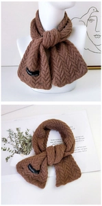 Gros plan sur une écharpe en tricot marron avec texture à chevrons et étiquette tissée