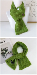 Détail d'une écharpe en maille verte avec boutons et étiquette tissée sur tissu texturé