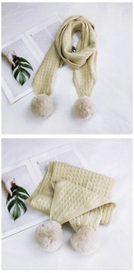 Detail of cable knit beige scarf featuring soft plush pompoms and warm wool texture
