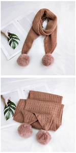 Detailed knit texture of solid brown scarf with fluffy pom-poms and cable stitch design