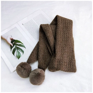 Detailed knit texture and soft pom-poms on long brown winter scarf for women