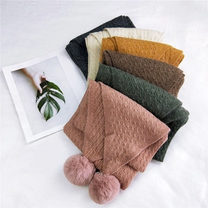 Knitted winter scarf with cable patterns and decorative fur pom-poms in various colors