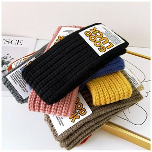 Detailed texture of colorful Good Luck letter knitted headbands stacked in multiple colors