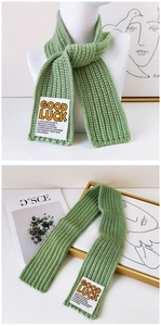 Detail of light green rib-knit scarf with GOOD LUCK woven label and soft wool texture