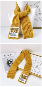 Detailed knit texture of bright yellow wool scarf with GOOD LUCK lettered patch