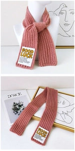 Detail of pink ribbed knit scarf showing the GOOD LUCK label and soft thick texture