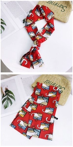 Detail of red narrow silk scarf featuring artistic cartoon cat illustrations and washing label