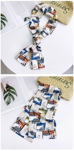 Detailed view of cream silk scarf with cartoon cat print layered on a stylish summer bag