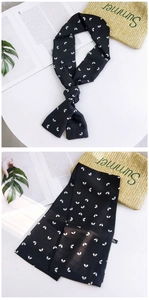 Macro detail of narrow black silk scarf with white heart print and fabric wash label
