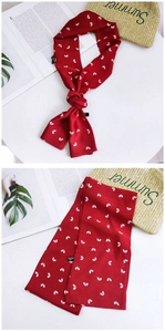 Detailed view of red chiffon skinny scarf with white heart prints and brand washing label