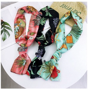Detailed close-up of three narrow satin scarves with tropical leaf and floral prints