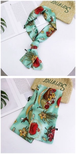 Detail view of a slim mint green floral twilly scarf with retro heart prints and artistic patterns