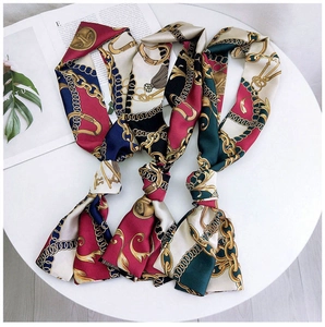 Detailed close-up of three narrow silk scarves with golden chain and tassel patterns