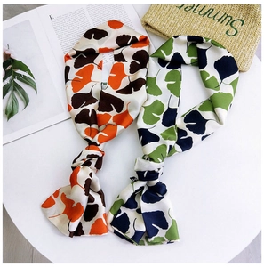 Detail of narrow silk scarves with ginkgo leaf prints in orange and teal colors