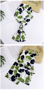 Detail of 100% polyester narrow silk scarf with green ginkgo leaf print and summer props