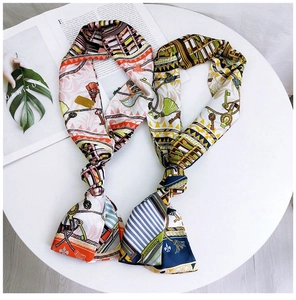 Detail of a narrow silk-like scarf featuring vintage key and chain patterns on a table
