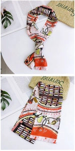 Detail showing colorful pattern silk scarf with classical motifs on a straw summer bag