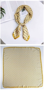 Detail of a yellow silk square scarf with geometric H pattern tied in a stylish loop knot