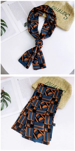 Detail of a blue and orange geometric silk scarf with an elegant knot on a white background