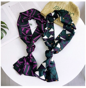 Flat lay of narrow silk scarves with geometric patterns on a white podium background