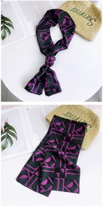 Close-up of narrow silk scarf with purple geometric print and smooth fabric texture