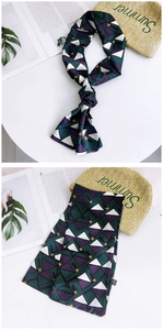 Detail of a geometric print silk scarf with green and purple patterns on a white table