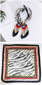Detail of zebra and leopard print silk scarf with red border accent laid on a magazine